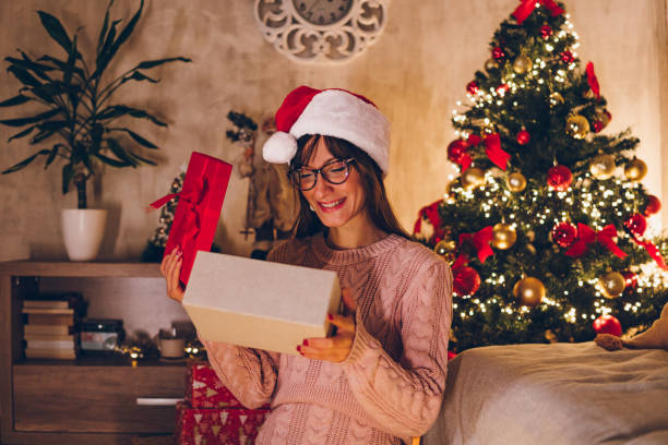 istock A young woman opens a Christmas present at home 1469154063