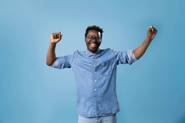 istock Cheerful black man celebrating his success against blue background. 1469154142