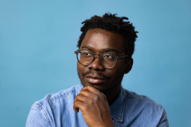 istock Young black man day dreaming against blue background. 1469154281