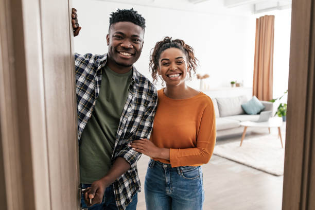 istock Cheerful Black Couple Opening Entry Door Posing At Home 1469154321