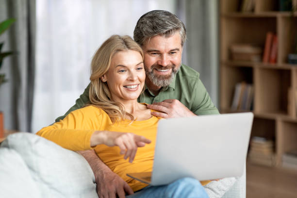 istock Beautiful Middle Aged Couple With Laptop Computer Resting Together At Home 1469154336