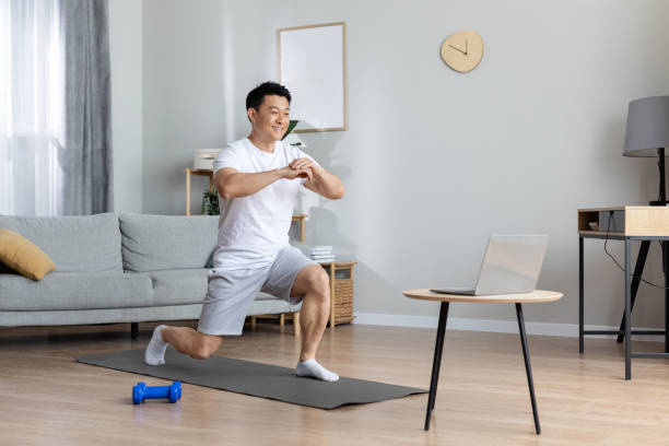 istock Motivated asian man exercising at home, using laptop 1469154402