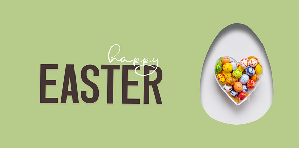 Happy Easter text and cut out Easter egg and colorful chocolate eggs in heart. Happy Easter greeting banner.