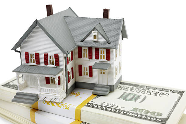 Model of home sitting atop a stack of 100 dollar bills stock photo