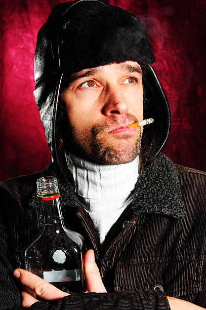 若い男性がタバコ、ボトルとコートのキャップ - eastern european caucasian one person alcoholism ストックフォトと画像