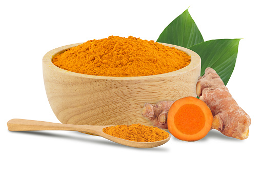 Turmeric powder in the wooden bowl with green leafs isolated on white background.With clipping path.