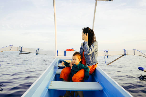asian woman with her baby enjoy the vacation with in a row boat asian woman with her baby enjoy the vacation with in a row boat bali boat tour stock pictures, royalty-free photos & images
