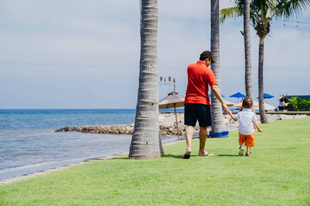 In early March, a 3-year-old Japanese girl in a white outfit plays with her father in his 30s on a sandy beach overlooking the Sea of Japan. A joyful springtime moment by the sea filled with warmth.