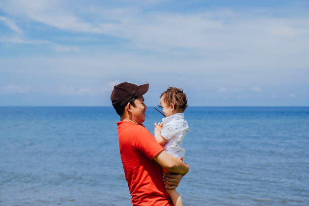 istock father holding up baby boy on the beach 1469160252
