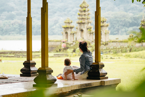 Asia, Indonesia, Bali, asian family sitting inside pavillion  enjoy the travel, in front of Tamblingan water temple, while sightseeing.