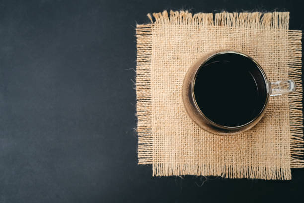 Cup of black coffee on a burlap napkin. flat layout, copy space