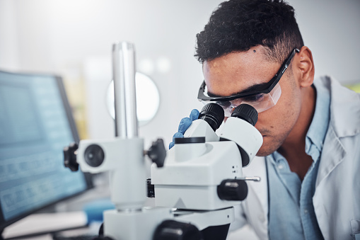 Science, microscope and man in laboratory for research, testing or medical analysis. Healthcare innovation,  scientist and male doctor with equipment to check sample, studying particles or bacteria.