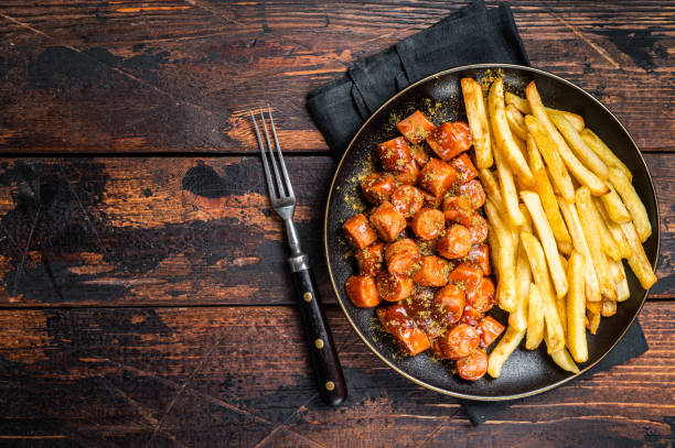 pasto tedesco currywurst, curry wurst con patatine fritte servite in un piatto. sfondo in legno. vista dall'alto. spazio di copia - currywurst foto e immagini stock