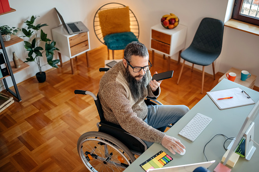 Person with disability working home office in wheelchair using computer