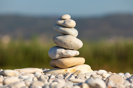 Stack of several rounded stones, on a beach in the morning, in a natural setting, arranged in balance and harmony