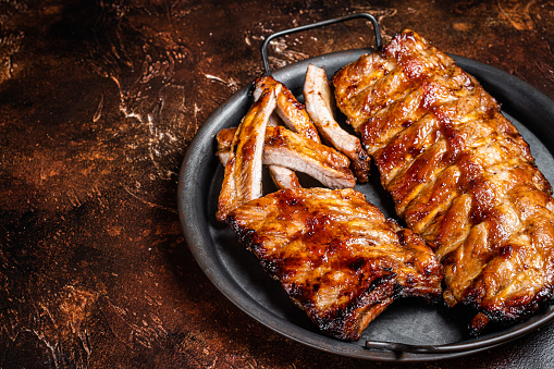 BBQ pork spare ribs St Louis with hot honey marinade in a steel tray. Dark background. Top view. Copy space.