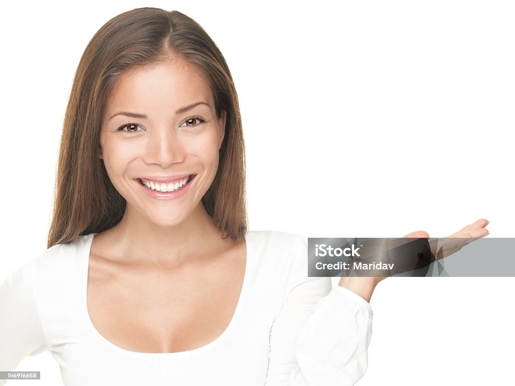 Smiling young woman with open hand to show something Smiling xwoman showing copy space for product with open hand palm - smiling friendly expression, Isolated on white background. Mixed Asian / Caucasian model. Click for more: Close-up Stock Photo