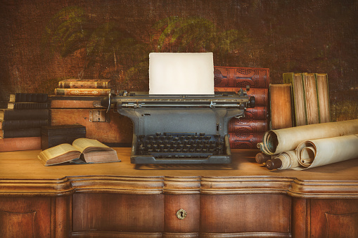 istock Desk with vintage typewriter holding an empty sheet of paper 1469167257
