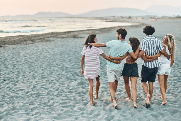 istock Back view of happy friends talking while walking embraced on the beach. 1469168760