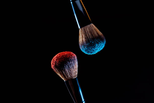 istock Cosmetics makeup brushes with red and blue colored powder on a dark background 1469168866