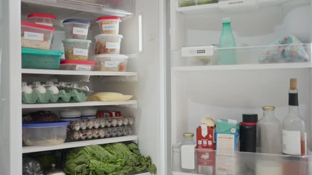 Labeled containers of food sitting on shelves in a fridge