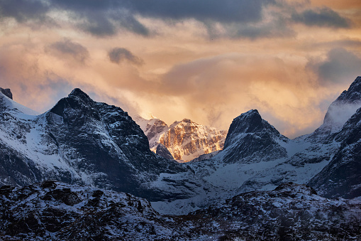 Snowcapped mountain range in Lofoten, Norway during winter golden hour.