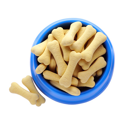 Bone shaped dog cookies and feeding bowl on white background, top view