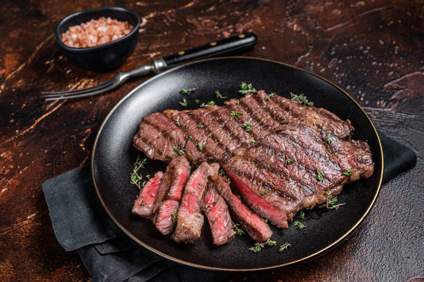 istock Barbecue denver strip beef meat steak on a plate. Dark background. Top view 1469171742