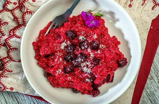 Ready-to-eat beetroot risotto food in white plate on table.