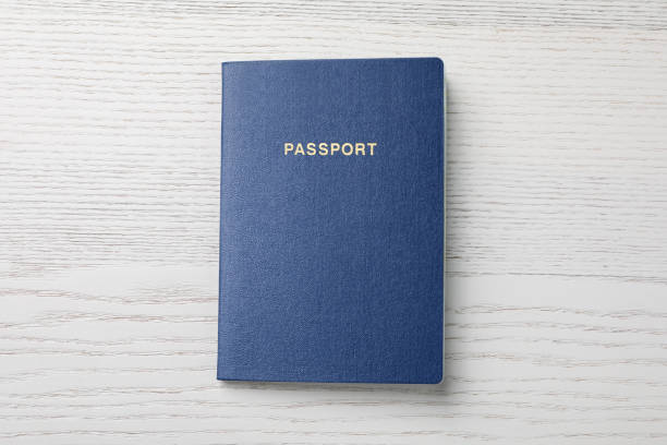 Blank blue passport on white wooden table, top view