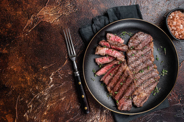 istock Barbecue denver strip beef meat steak on a plate. Dark background. Top view. Copy space 1469171778