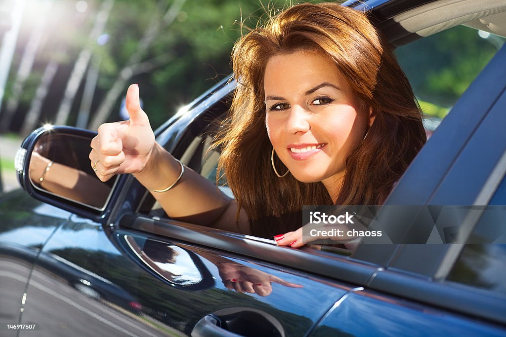 Young woman looking out of car Young woman looking out of car and showing success handsign. 20-29 Years Stock Photo