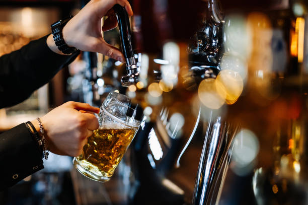 mão de barman homem na torneira de cerveja derramando uma cerveja de pressão em vidro servindo em um restaurante ou pub - pale ale - fotografias e filmes do acervo