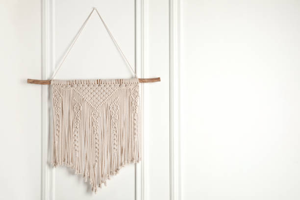 istock Stylish beige macrame hanging on white wall. Space for text 1469178110