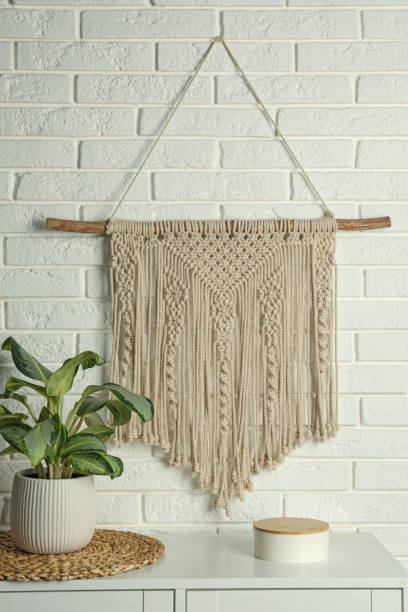 istock Beautiful macrame hanging on white brick wall in room. Decorative element 1469178504