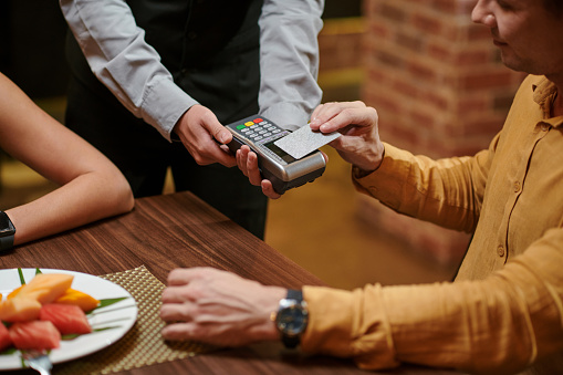Man paying with credit card for romantic dinner at restaurant