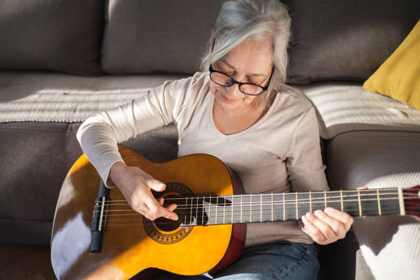 istock Senior woman playing guitar at home 1469187611