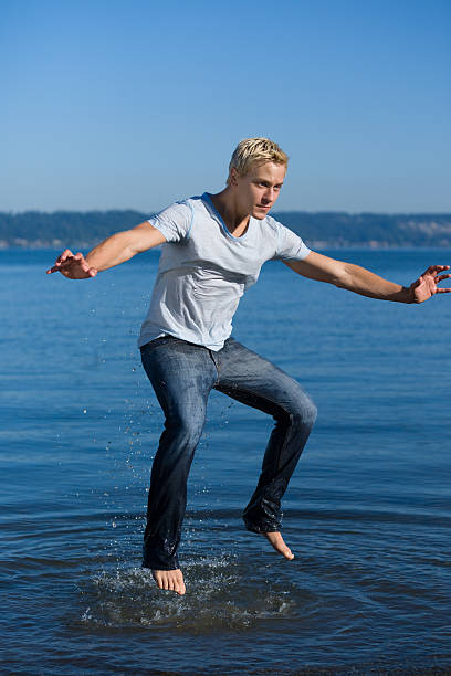 Young man jumping out of water stock photo