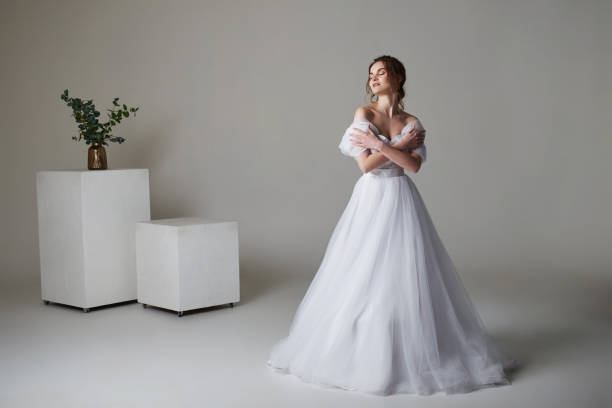istock A beautiful young bride model in long lace dress in minimalist white studio interior. Wedding photography. 1469193318