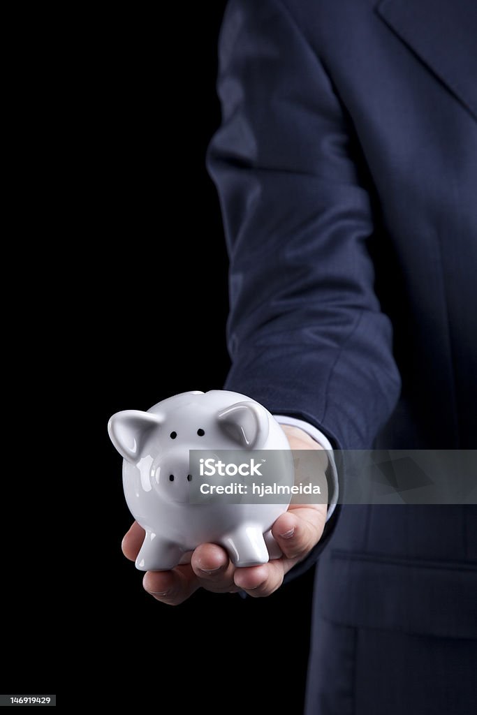 Banking service Businessman giving a piggy bank to you (isolated on black) Banking Stock Photo