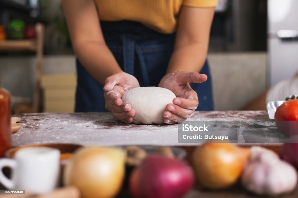 수제 피자를 만들기 위해 반죽을 반죽하는 인간의 손을 클로즈업합니다 앞치마와 손이 반죽을 반죽합니다 빵집에서 손으로 반죽 만들기 ...