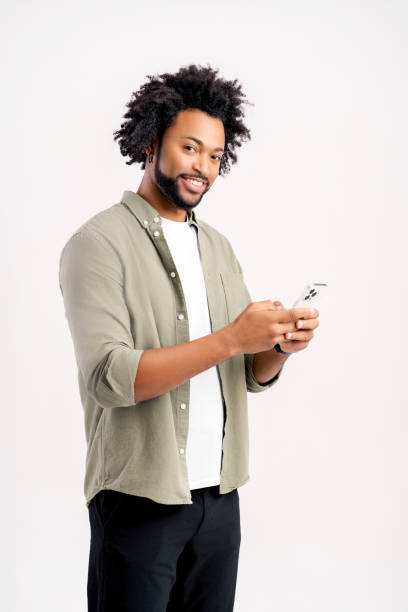 istock Smiling african 30s man in casual wear using smartphone standing isolated on white 1469198886