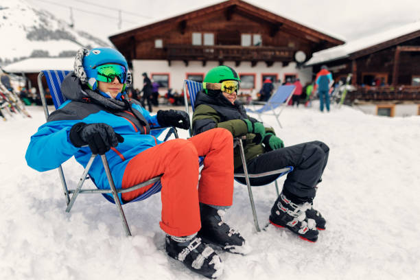 teenage boys enjoying a break in skiing - sitting on sun beds and looking at view. - apres ski winter friendship ski imagens e fotografias de stock