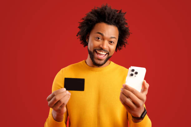 istock Hilarious African American curly young man using smartphone app for transferring money, shopping or making purchases online 1469199689