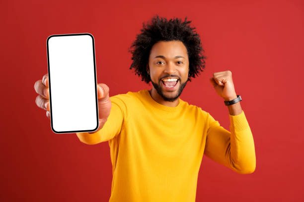 istock Excited hilarious African American curly young man showing smartphone with empty screen and screaming yes 1469199690