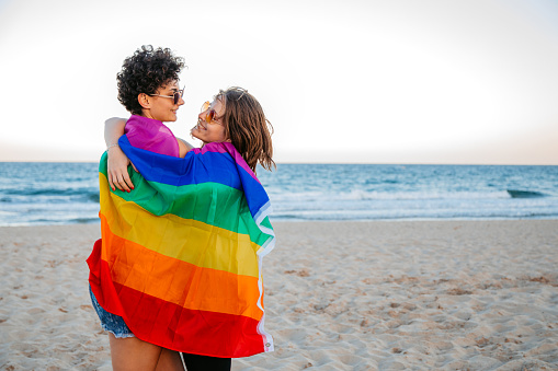 Beautiful young lesbian couple having fun on the beach in Albena, Bulgaria. Wrapped up in a pride flag.