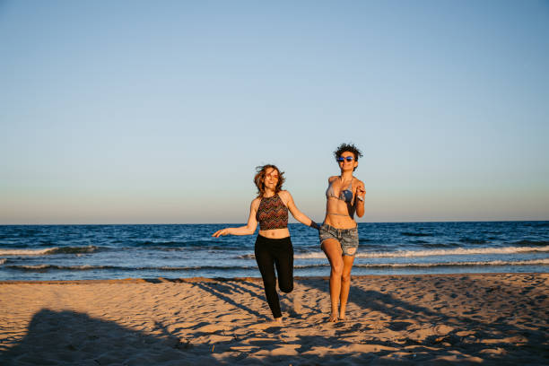 istock Young Lesbian Couple Running On The Beach 1469200098