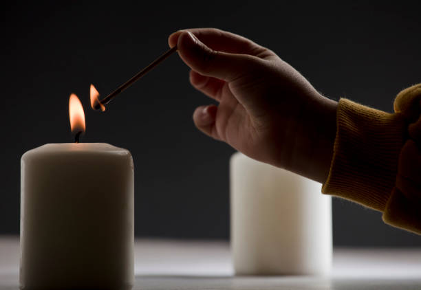 istock lit candle with child hand and fire stick match 1469200952
