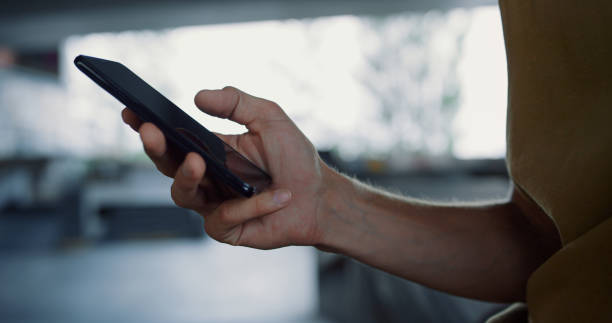 istock Young man typing message on mobile phone skatepark. Male hands using smartphone 1469202175