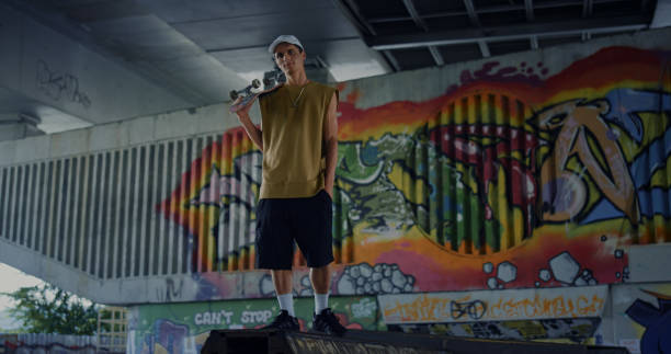 istock Relaxed man having break after skateboarding at skatepark with graffiti wall. 1469203217